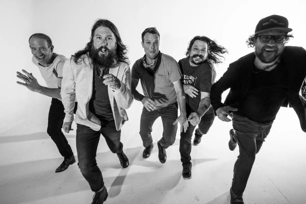 five men being silly and running around in a white room