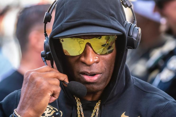 A man in reflective sunglasses speaks into a headset.