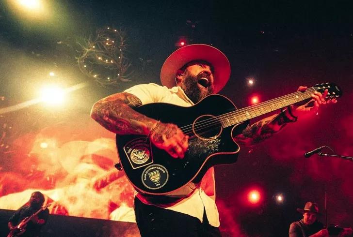 man wearing cowboy hat smiling and playing guitar
