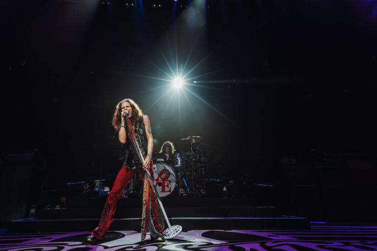 man in red pants screaming into a microphone on stage