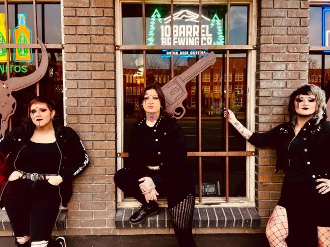 three women standing outside of a brick building with big windows