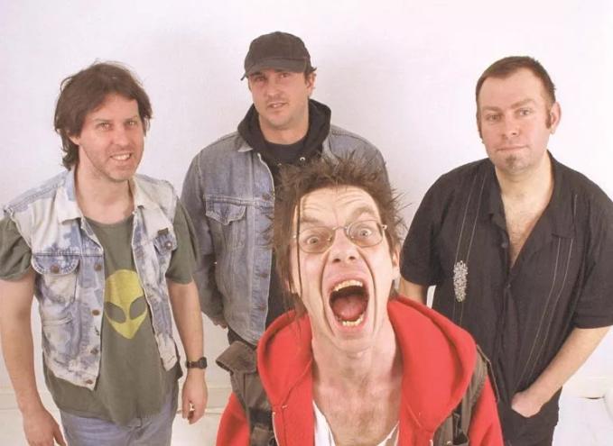 punk musicians posing for a photo against a pale pink background