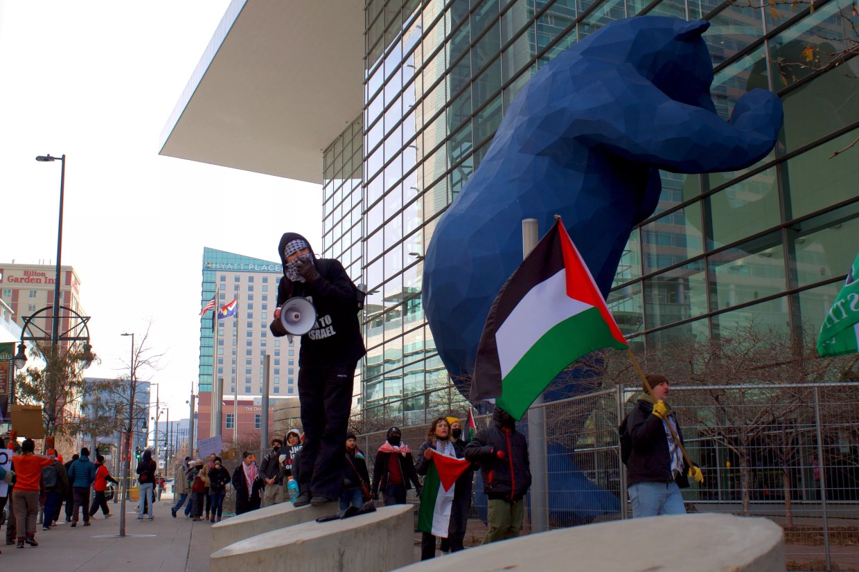 Pro-Palestine protestors hold signs and flags outside of the Global Conference for Israel at the Colorado Convention Center.