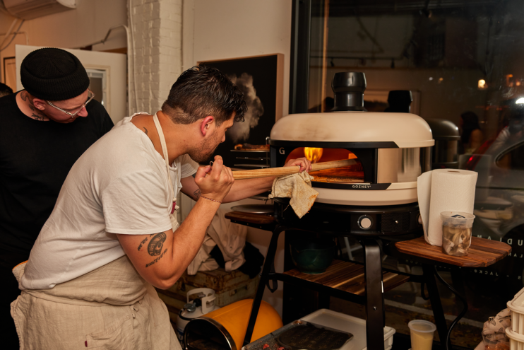 a man pulling a pizza out of an oven