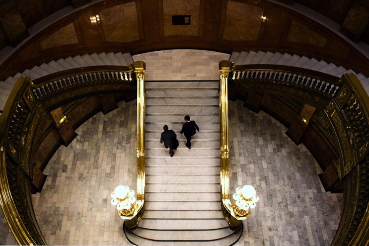 Two men in suits walk up the stairs of the Colorado Capitol building.