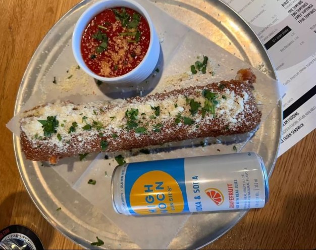 a giant mozzarella stick next to a can of high noon