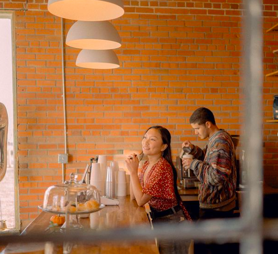 two people standing behind a counter in a coffee shop