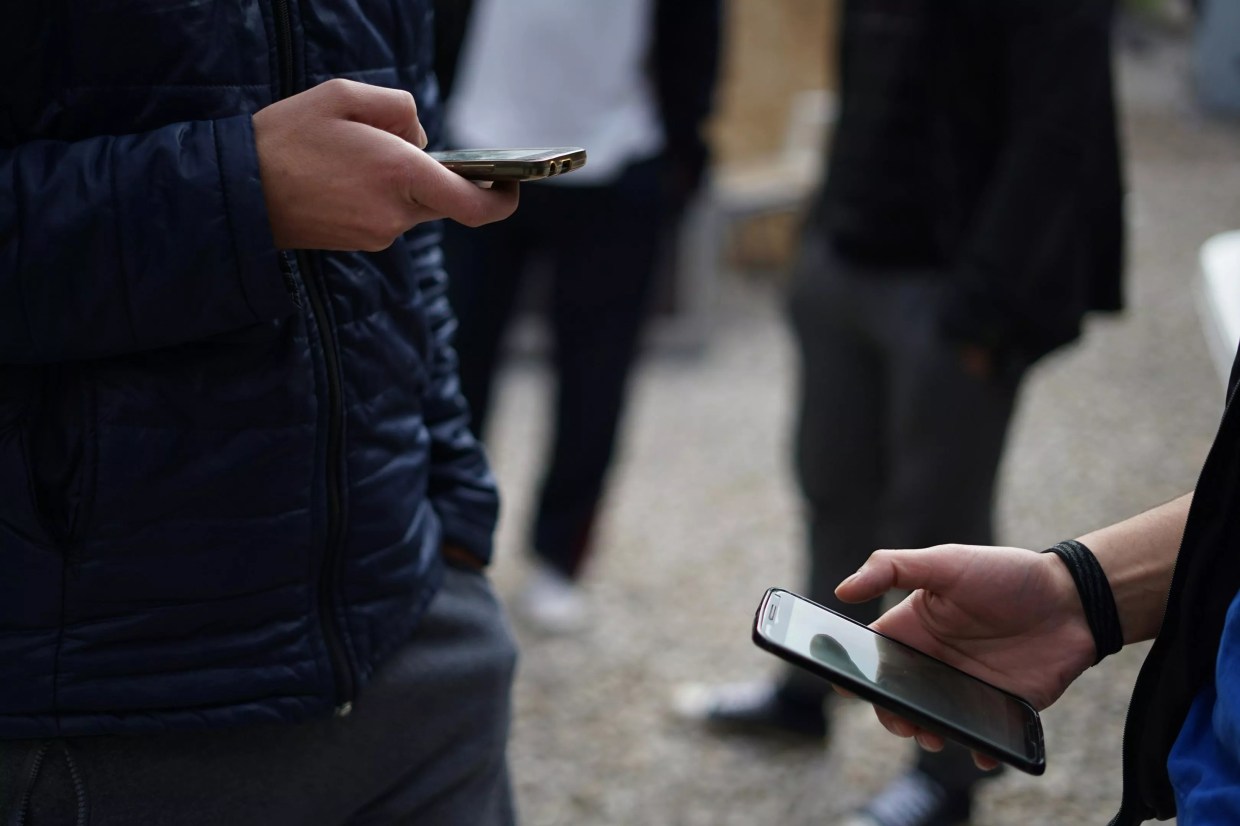 Two people holding cell phones, scrolling on social media.