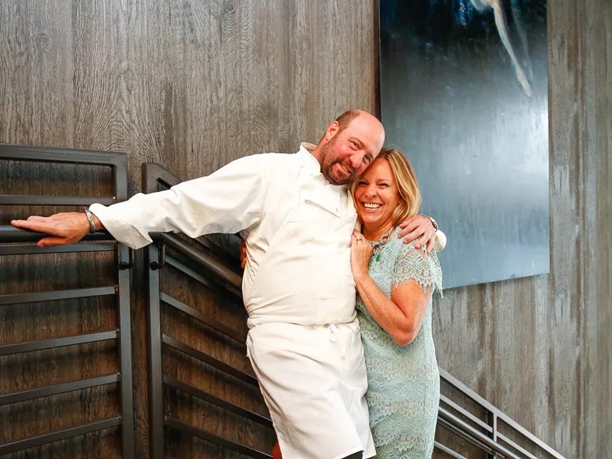 man in chef outfit hugging wife