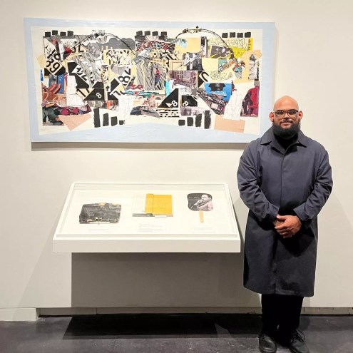man standing next to his artwork