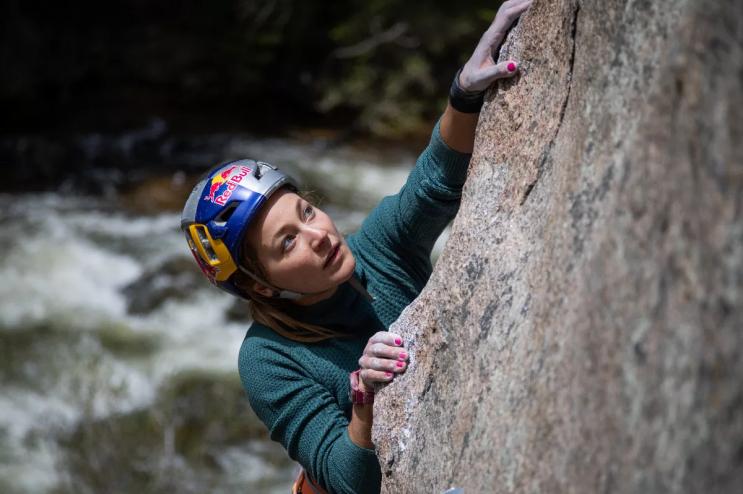 A woman climbs a rock.