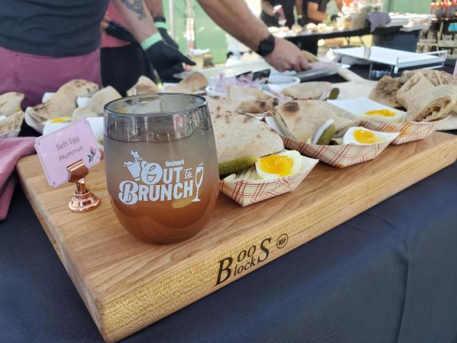a cup on a cutting board next to samples of hummus
