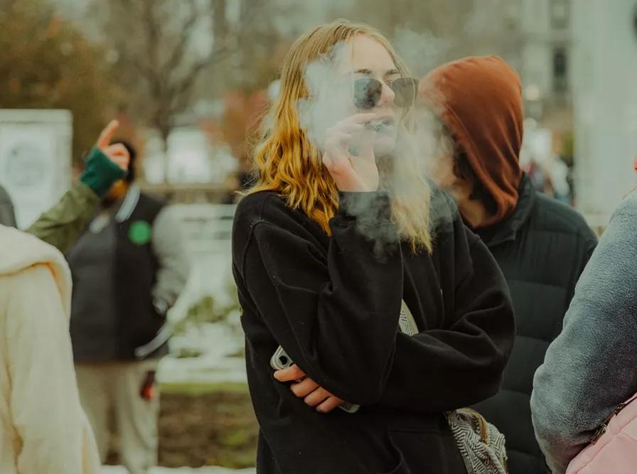 Young woman smokes joint outside