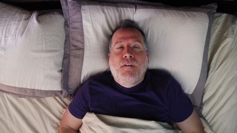 Sleeping old man snores in bed