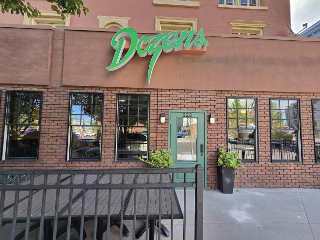 green sign that says "dozens" on a brick building