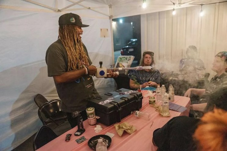 A man blows smoke with a device.