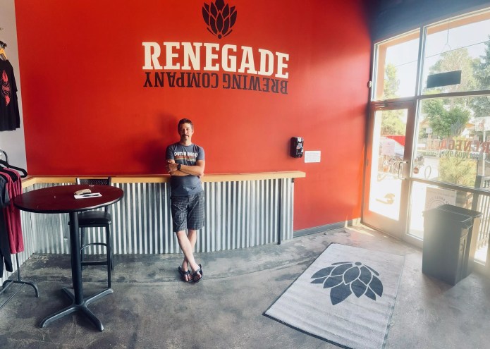 Man standing in front of a brewery sign.