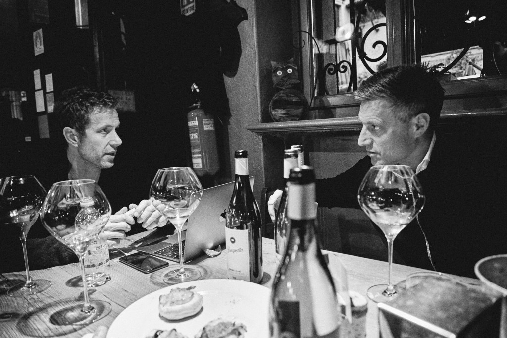 black and white photo of two men sitting at a table with wine glasses