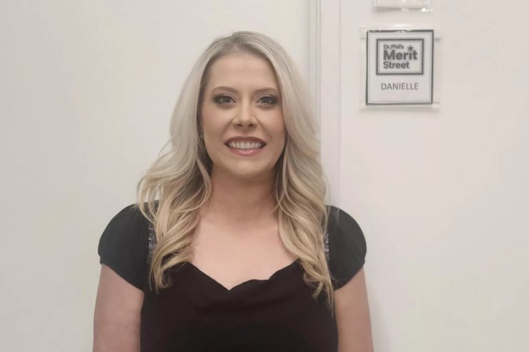 A woman stands in front of a door smiling.