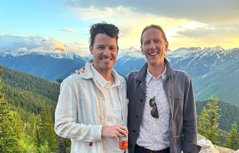 two men posing with a mountain backdrop