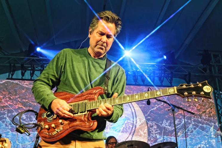 man playing guitar with lights in the background