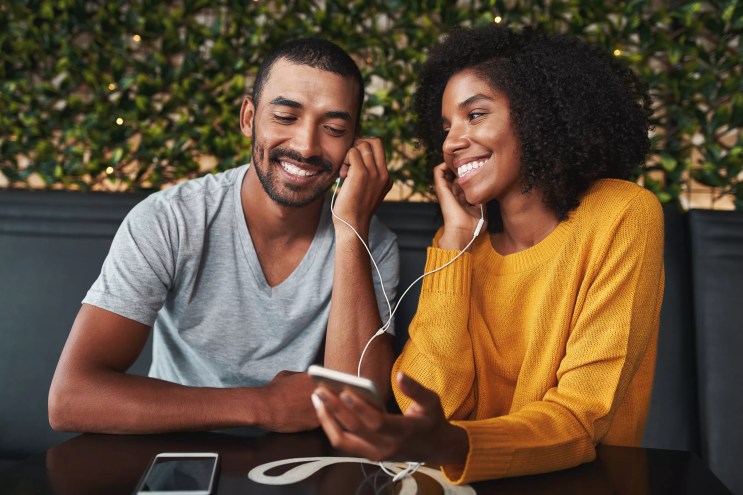 two people listening to music through the same set of headphones