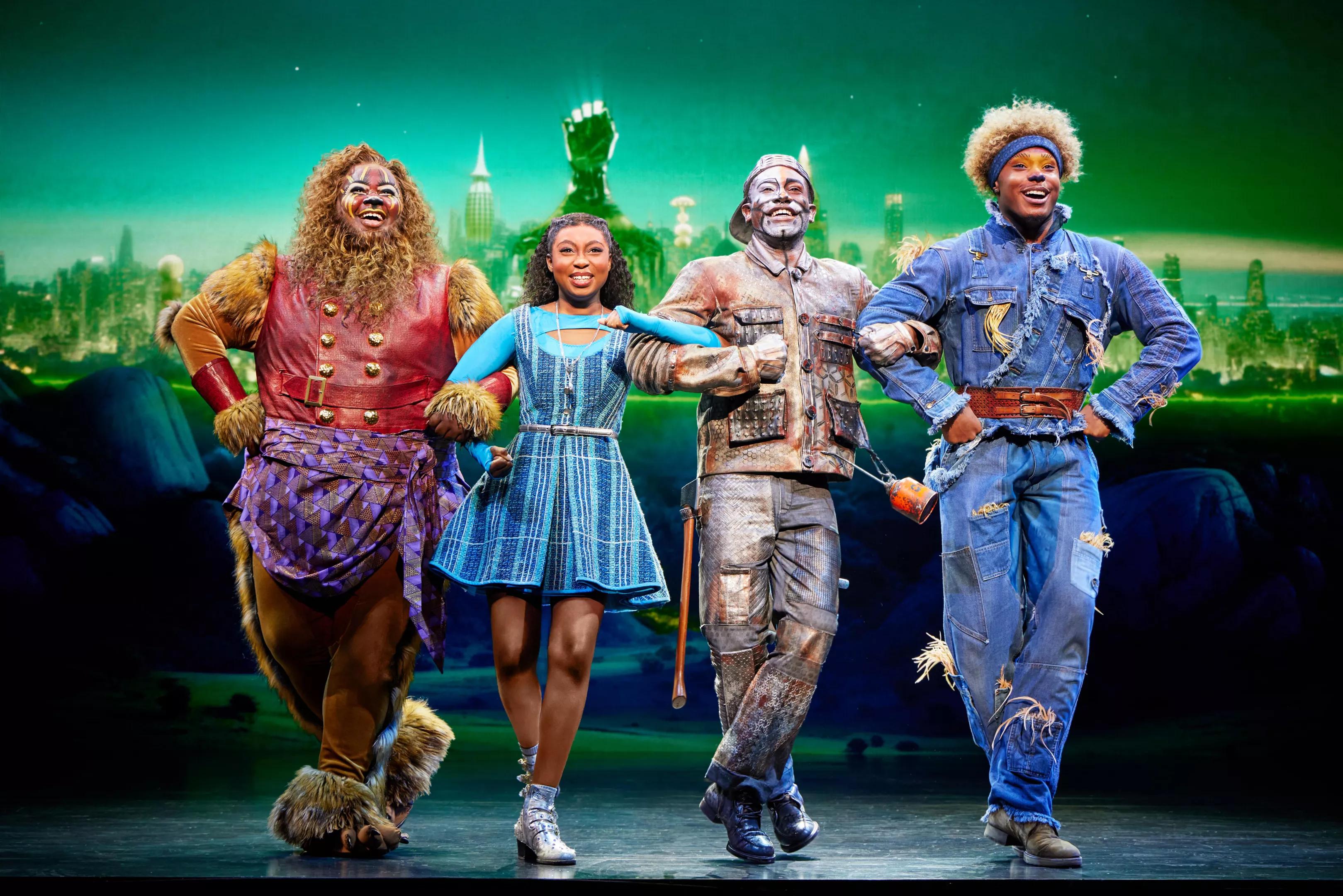 The Lion, Dorothy, Tin Man and Scarecrow walk together.