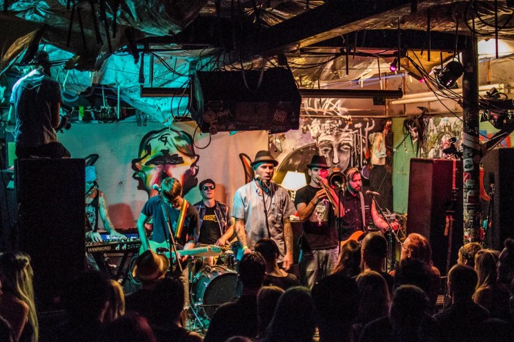 A band plays on stage to a crowded room