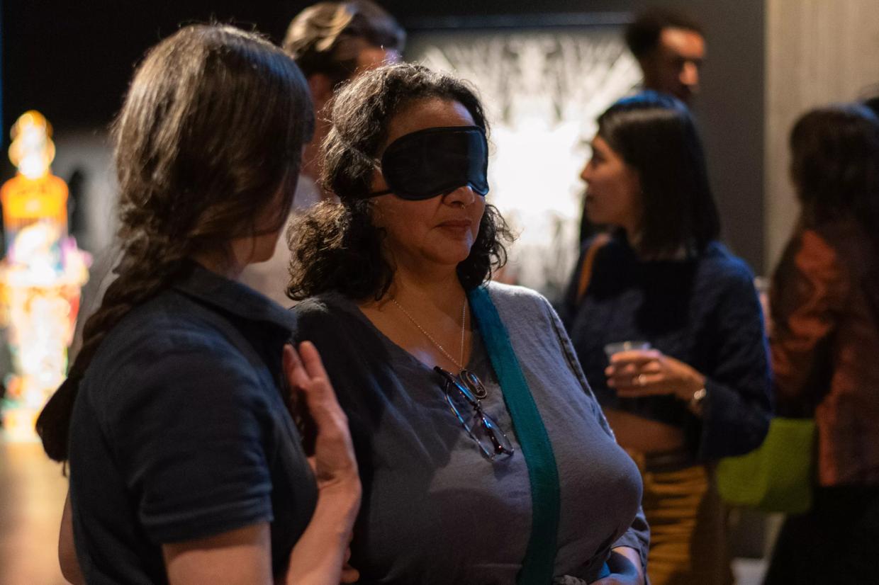 Blindfolded woman explores an art gallery.