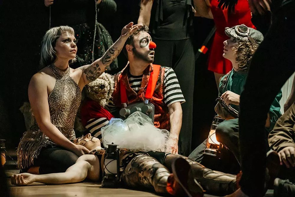 Clowns sit on the ground together.