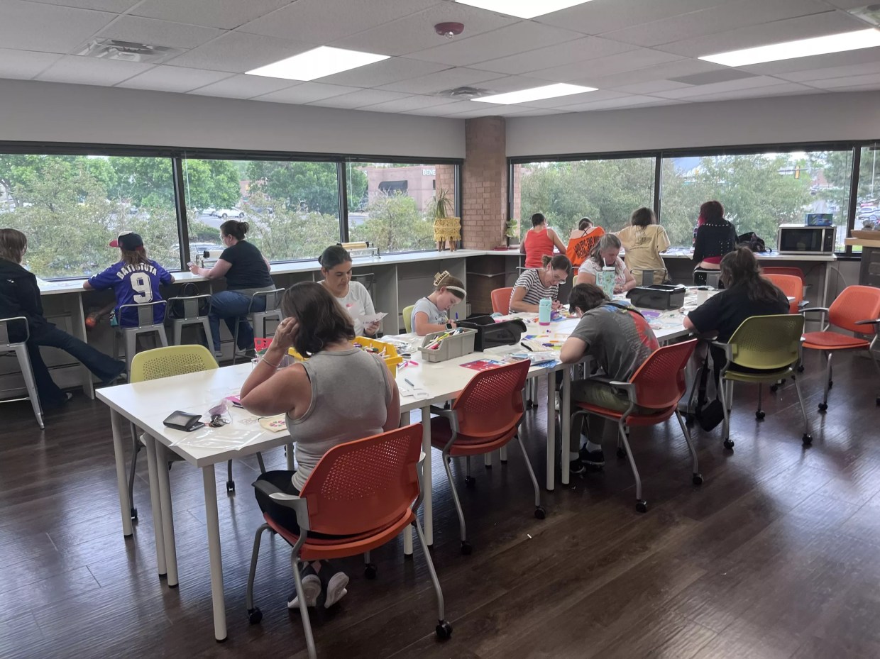People sit around a table working together to assemble Kynd Kits.