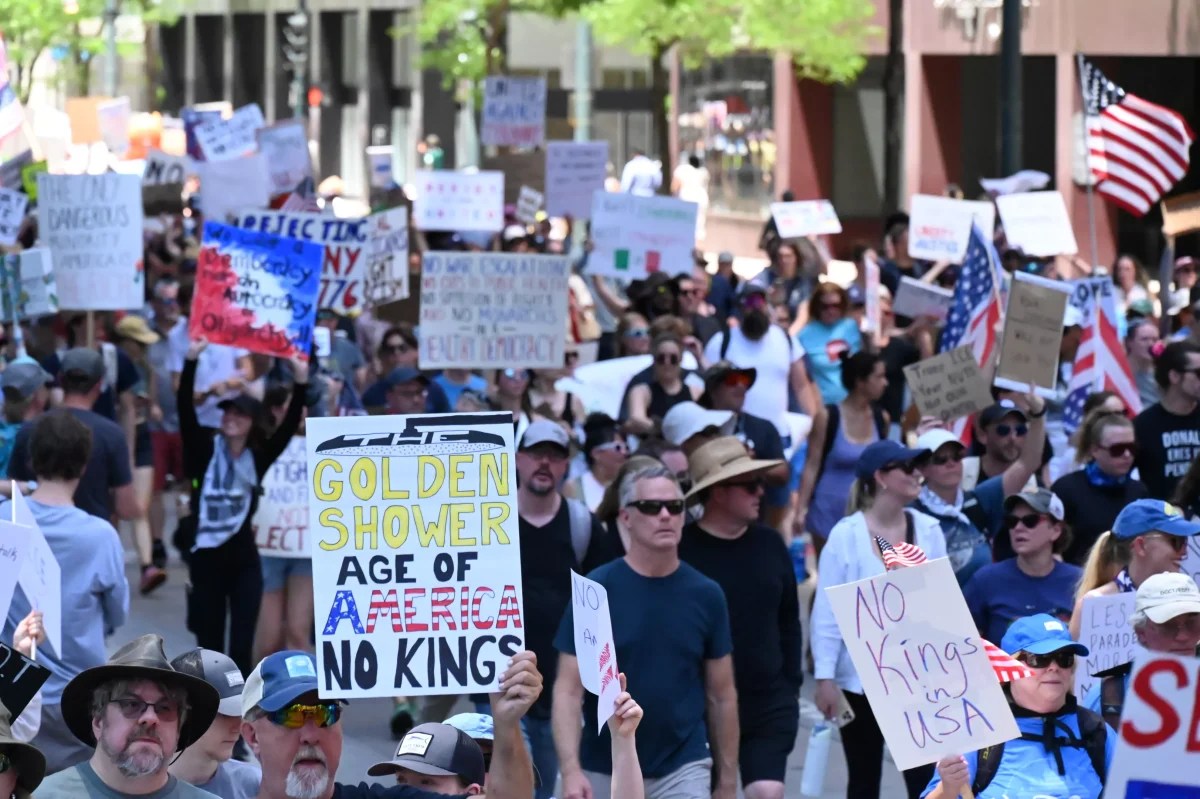 Man holds sign during Denver No Kings protest march