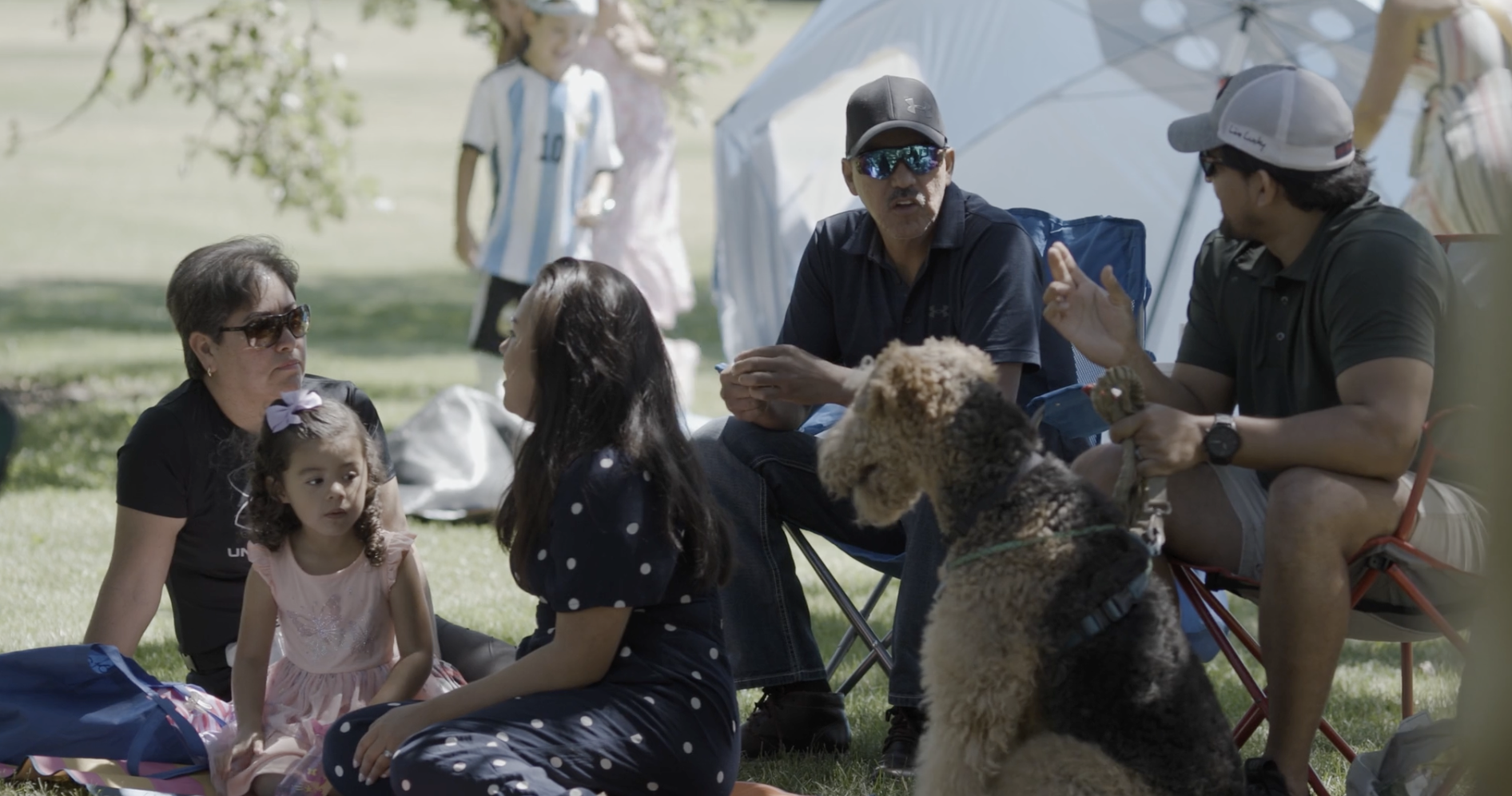 People and a dog sit together in the grass