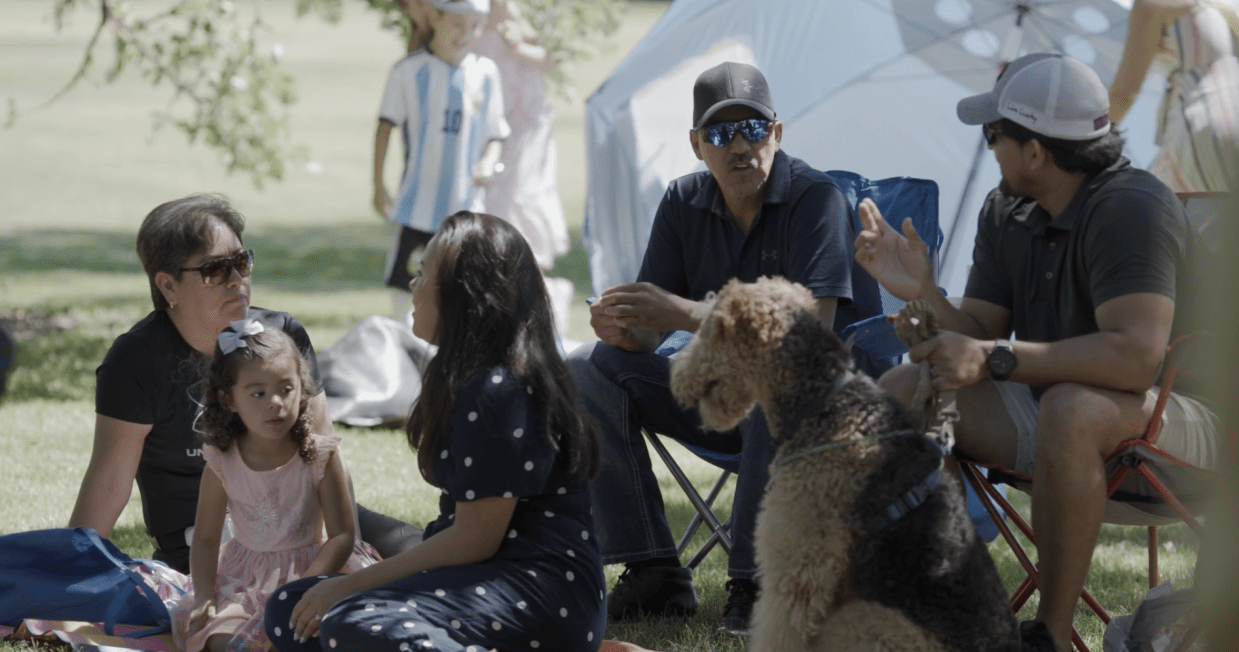 People and a dog sit together in the grass