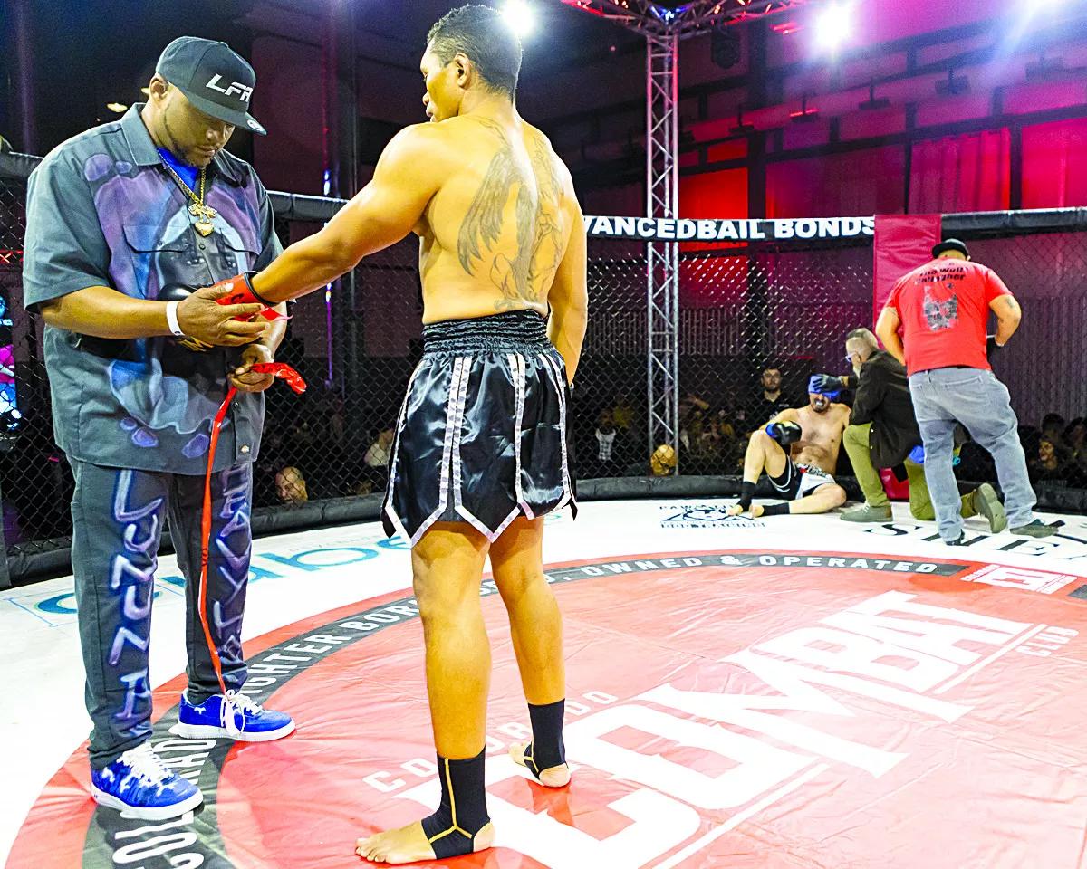 man taking gloves off fighter.