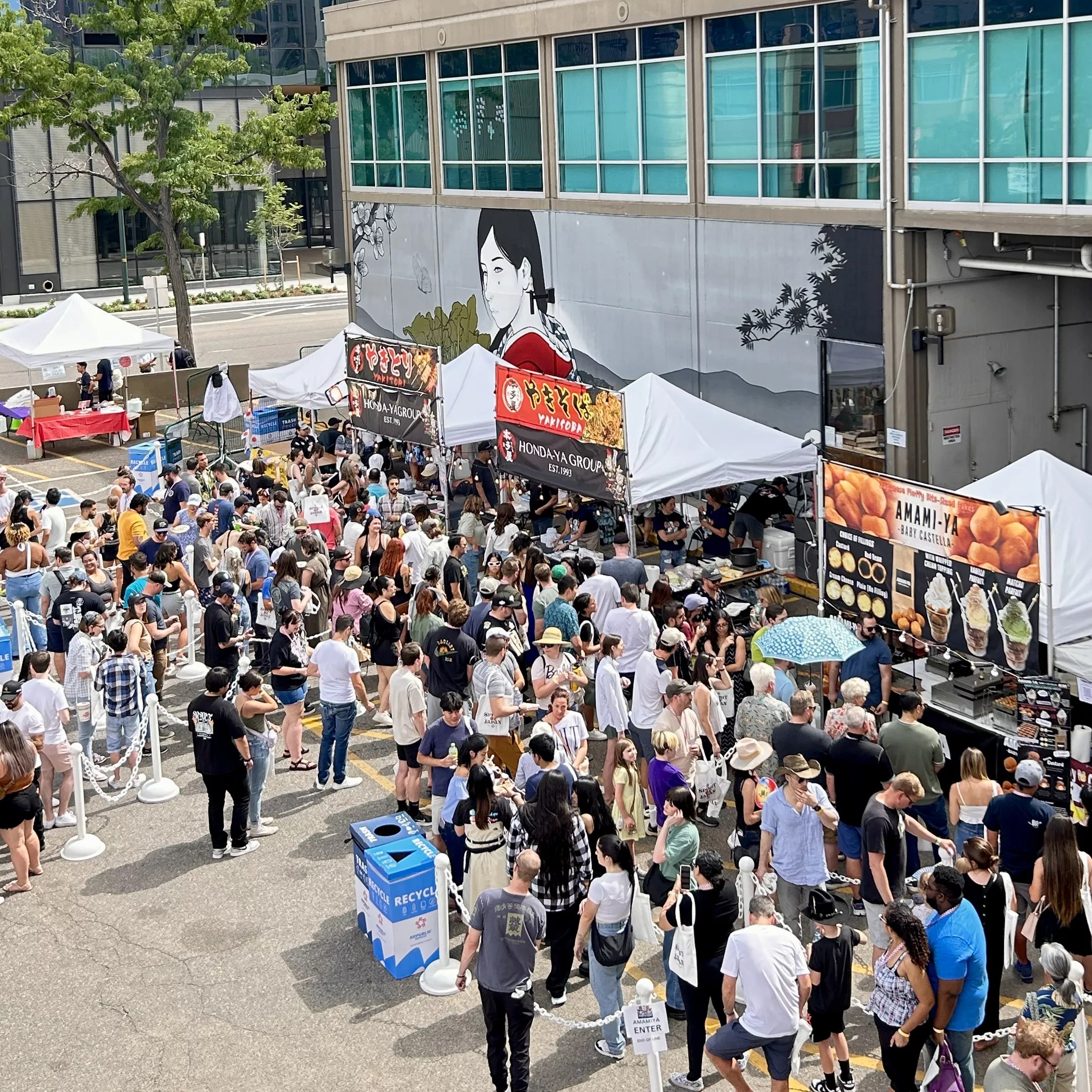 A crowd of people surround food booths